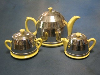 A 3 piece yellow glazed pottery tea service with chromium plated insulators with teapot, sugar bowl and cream jug