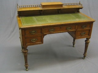 A late Victorian honey oak writing table, the raised back with pierced three-quarter gallery, the centre fitted an inkwell, the top with inset tooled leather writing surface above 1 long and 4 short drawers, raised on turned and fluted supports  46"