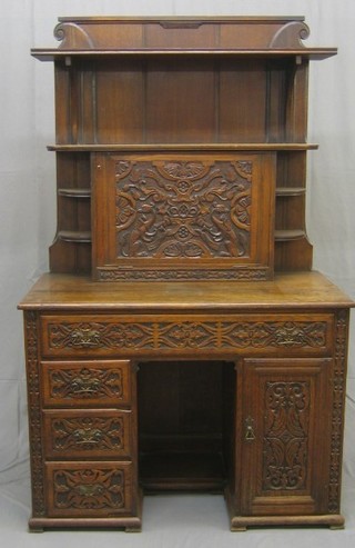 A Victorian Art Nouveau carved oak bookcase on desk, the raised upper section fitted shelves and niches and having fall front carved throughout with square and compasses to the centre, the interior revealing pigeon holes and 3 short drawers, the base fitted a kneehole pedestal desk with 1 long drawer flanked by a cupboard and 3 short drawers, raised on ogee bracket feet, 42"