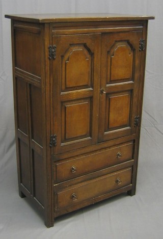 A 17th Century style oak cabinet enclose by panelled doors, the base fitted 2 drawers 30"