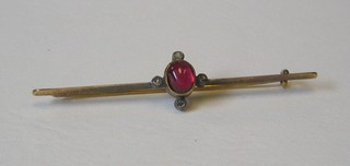 A lady's "gold" bar brooch set a cabouchon cut red stone supported by white stones