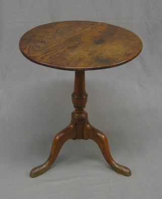 A 19th Century elm circular tilt top table, raised on turned column and tripod supports 22"