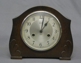 A 1930's 8 day striking mantel clock with silvered dial and Arabic numerals contained in an oak arched case