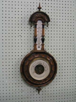 A Victorian German aneroid barometer and thermometer contained in a carved walnut wheel case