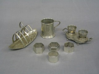 An English pewter 2 bottle egg cruet, a planished pewter toast rack, 4 various pewter napkin rings and a tankard