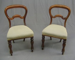 A set of 4 Victorian mahogany framed balloon back dining chairs with shaped mid rails and upholstered seats, raised on chamfered turned supports