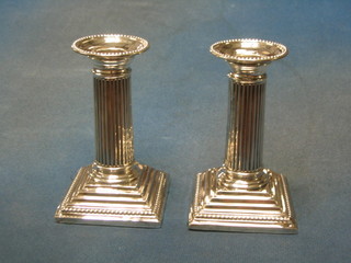 A pair of Victorian silver reeded candlesticks, raised on stepped bases with detachable sconces, London 1886 with bead work borders, 5" (marks rubbed)