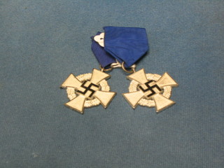 2 Nazi period white metal waisted crosses, the centre with black enamelled swastika within reeds, hung on blue ribbons