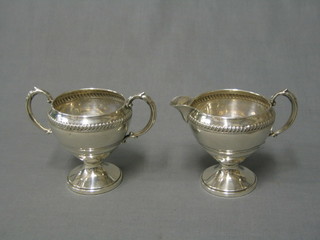 An American Sterling silver twin handled sugar bowl and cream jug with embossed decoration,