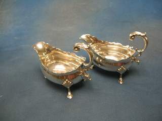 A handsome pair of George III silver sauce boats with wavy cut borders and C scroll handles, armorial decoration raised on 3 hoof supports London 1819, 12 ozs