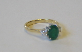 A lady's 18ct gold dress ring set an oval cut emerald supported by 2 diamonds