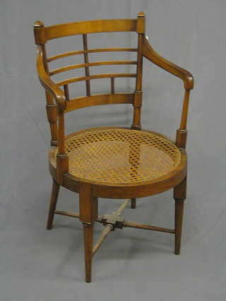 A Victorian walnut tub back open arm chair with woven cane seat raised on turned supports with X framed stretcher