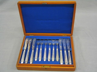 A canteen of 12 engraved silver plated fish knives and forks with bead work borders contained in a walnut canteen box