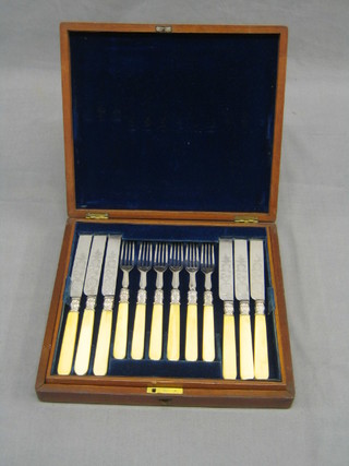 A set of 12 Victorian engraved silver plated fruit knives and forks with ivory handles, contained in a walnut canteen box
