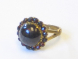 A lady's gilt metal ring set a cabouchon cut garnet supported by garnets