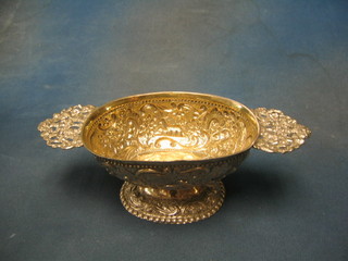 An oval embossed Dutch silver bowl with pierced twin handles and parcel gilt interior, embossed deer and birds amidst park land, raised on an oval spreading base,