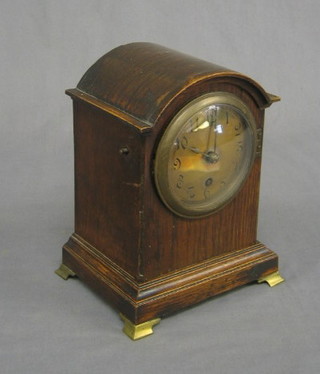 A 1920's 8 day bracket clock with silvered dial and Roman numerals contained in an arch oak shaped case, raised on brass bracket feet 6"