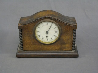 A 1930's bedroom timepiece contained in an arched oak case