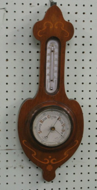 An Edwardian aneroid barometer and thermometer contained in an inlaid mahogany wheel case