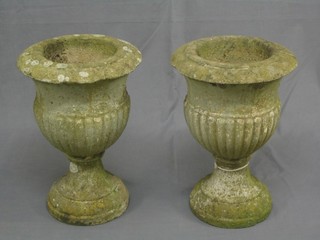 A pair of well weathered 19th Century circular stone urns of trumpet form, the bodies with demi-reeded decoration 17" high, 12" diameter