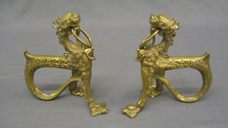 A pair of brass fire dogs in the form of Dogs of Fo