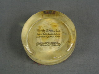 A circular Hardy's Bros glass paperweight marked Hardy Bros Ltd Fishing Rod and Tackle Makers Alwick England, 61 Palmall London, 14 Moult St Manchester, 101 Princes St Edinburgh 3" (some discolouration to the paper)