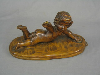 A carved wooden figure of a reclining cherub raised on an oval base (3 fingers and thumb f, old repair to arm, some worm) 60"