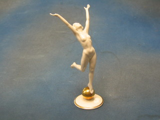 An Art Deco porcelain figure of a standing naked lady raised on a gilt globe, the base marked LHS 10"