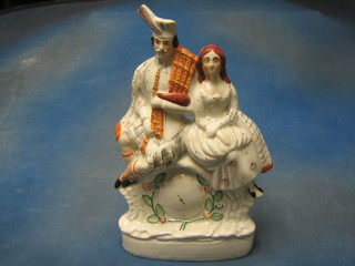 A 19th Century flat back Staffordshire figure in the form of a clock with seated Scotsman and lass 14"