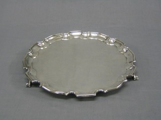 A circular silver plated salver with bracketed border, raised on ball and claw feet 12"