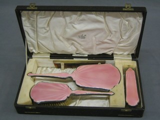 A silver plated and pink enamelled back dressing table set comprising hand mirror, hair brush, clothes brush and comb, cased