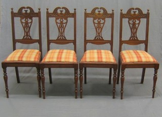 A set of 4 Edwardian carved mahogany dining chairs with broken pediment cresting rail, pierced vase splat backs and upholstered seats, raised on turned supports
