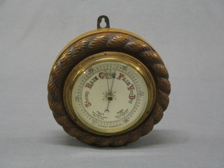A 19th Century aneroid barometer with porcelain dial contained in a circular carved oak case with rope edge border, 8"