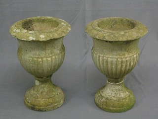 A pair of well weathered concrete circular stone urns of trumpet form, the bodies with demi-reeded decoration 17" high, 12" diameter,