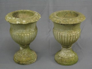 A pair of well weathered concrete circular stone urns of trumpet form, the bodies with demi-reeded decoration 17" high, 12" diameter