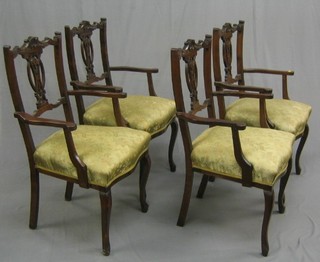 A set of 4 Edwardian carved walnut open arm chairs with carved cresting rails, pierced vase splat backs and upholstered seats, raised on cabriole supports