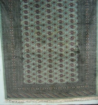 A contemporary Pakistan green ground Bokhara rug with numerous octagons to the centre within multi-row borders 112" x 74"