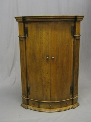 A good quality bleached oak bow front corner cabinet, flanked by a pair of fluted columns the base fitted 1 long drawer, 30"