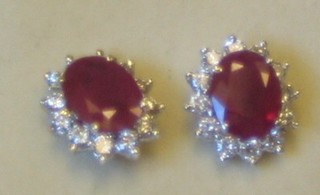 A pair of lady's 18ct gold ear studs set oval cut rubies surrounded by diamonds