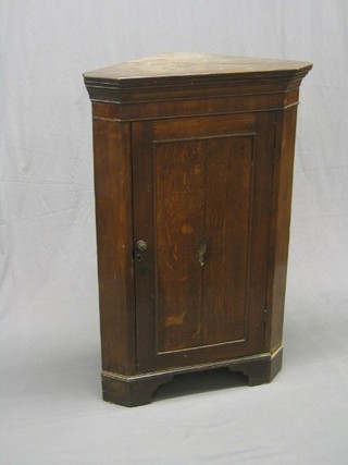 A 19th Century Country oak corner cabinet enclosed by a panelled door, raised on later bracket feet 28"