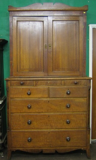 A 19th Century Country oak cabinet on chest, the upper section with moulded cornice fitted a cupboard enclosed by panelled door, the base frieze fitted 3 short drawers above 2 short and 3 long drawers, raised on splayed bracket feet 49"