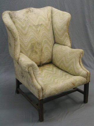 An 18th Century mahogany framed wing back armchair upholstered in green material (wing frame slightly loose)