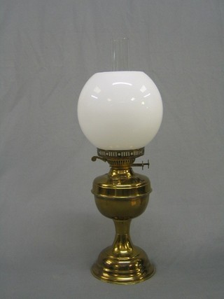 A brassed oil lamp with white glass shade and chimney