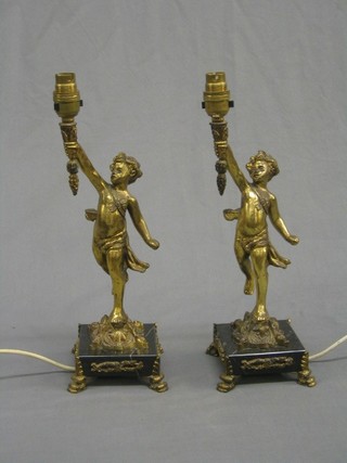A pair of gilt metal and marble table lamps in the form of cherubs holding torches, raised on black marble bases, 15"