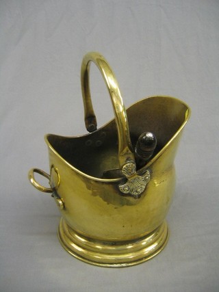 A brass helmet shaped coal scuttle together with a shovel