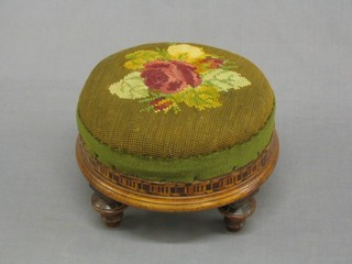 A circular Victorian inlaid mahogany footstool with Berlin wool work supports raised on 3 turned supports