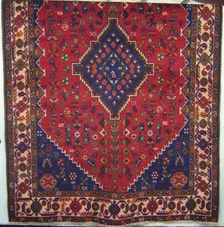 A contemporary red ground Persian carpet with blue diamond to the centre within multi-row borders 113" x 79"