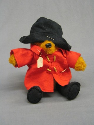 A  Paddington bear with black hat and red duffel coat