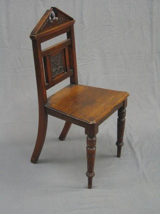 An Edwardian carved mahogany hall chair with broken pediment to the back, having a solid seat and raised on turned supports