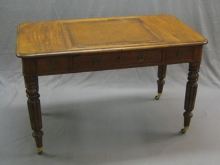 A William IV mahogany writing table, the centre section fitted a hinged panel, fitted 1 long drawer flanked by 2 dummy drawers, raised on turned and reeded supports ending in replacement brass caps and castors, 48"